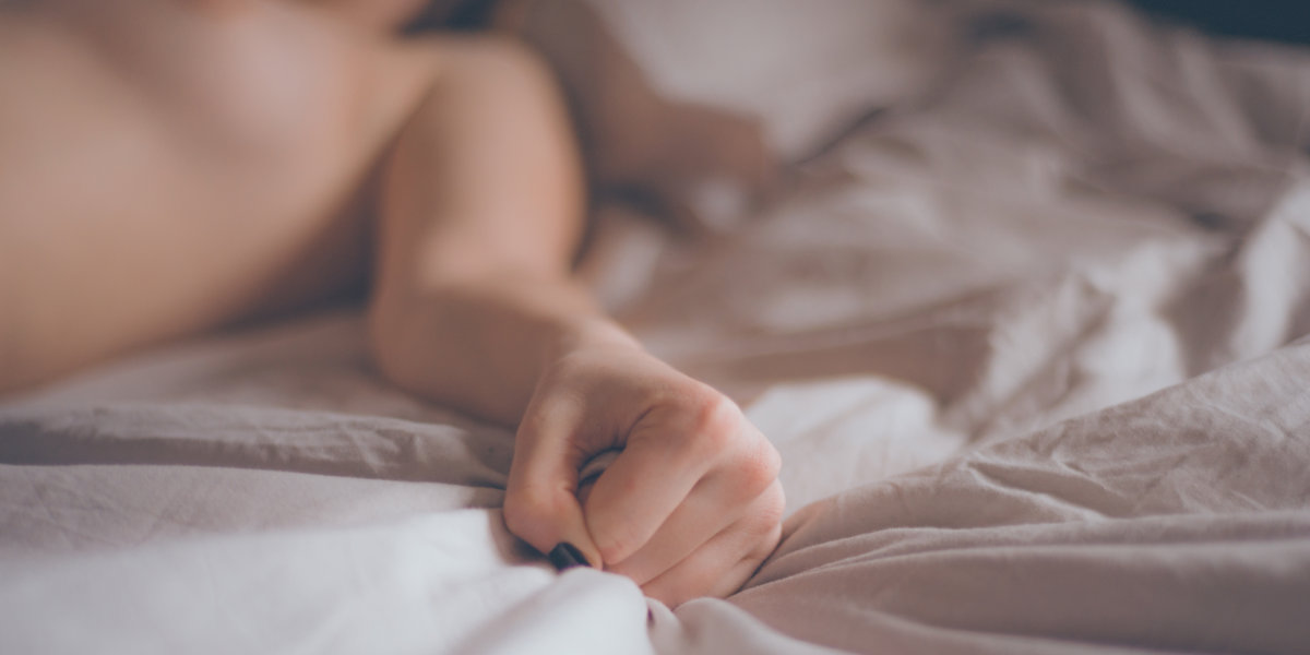 Hand sign orgasm of woman on white bed. Hand of female pulling 